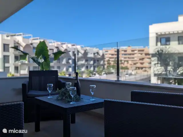 Luxe appartement met zwembadzicht huren in Spanje, Costa Blanca, Alicante - appartement Het ruime balkon biedt een prachtig uitzicht op het sprankelende zwembad en de groene tuin eromheen. De ligging zorgt ervoor dat je de hele dag kunt genieten van de zon, terwijl er ook schaduwrijke plekken zijn voor warme dagen.