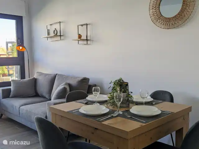Luxe appartement met zwembadzicht huren in Spanje, Costa Blanca, Alicante - appartement De knusse woonkamer straalt warmte en gezelligheid uit, met comfortabele meubels en een sfeervolle inrichting. Door de grote ramen heb je een prachtig uitzicht op het zwembad, wat een heerlijk gevoel van ruimte en rust geeft.