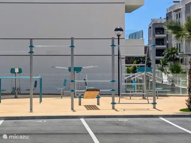 Luxe appartement met zwembadzicht huren in Spanje, Costa Blanca, Alicante - appartement Het gebouw is nieuw en luxe, met moderne voorzieningen voor alle leeftijden. Er is een speeltuin voor de kinderen, een jeu de boules baan en een buiten gym voor sportliefhebbers. Daarnaast beschikt het complex over een eigen parkeergarage en een gesloten, bewaakte ingang en uitgang.