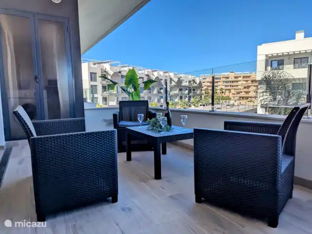 Luxe appartement met zwembadzicht huren in Spanje, Costa Blanca, Alicante - appartement Het ruime balkon biedt een prachtig uitzicht op het sprankelende zwembad en de groene tuin eromheen. De ligging zorgt ervoor dat je de hele dag kunt genieten van de zon, terwijl er ook schaduwrijke plekken zijn voor warme dagen.