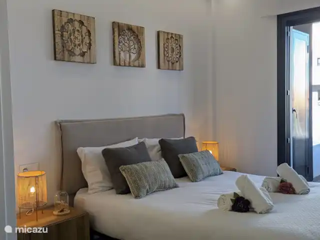 Luxe appartement met zwembadzicht huren in Spanje, Costa Blanca, Alicante - appartement Slaapkamer 1: Deze ruime slaapkamer is voorzien van een grote inbouwkast en een moderne en-suite badkamer met luxe voorzieningen. Via de openslaande deuren heb je directe toegang tot het balkon, waar je kunt genieten van een prachtig uitzicht op het zwembad.