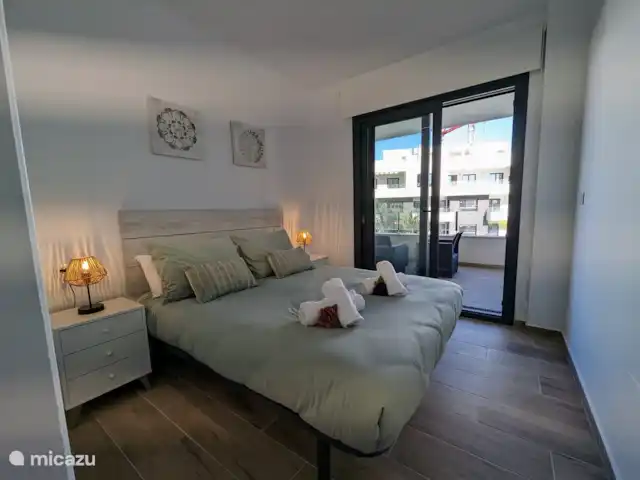 Luxe appartement met zwembadzicht huren in Spanje, Costa Blanca, Alicante - appartement Slaapkamer 2 heeft directe toegang tot het balkon, waar je kunt genieten van een prachtig uitzicht. De kamer is voorzien van een ruime inbouwkast en maakt gebruik van de tweede badkamer, die zich vlakbij bevindt. Een comfortabele en praktische ruimte voor een heerlijk verblijf.