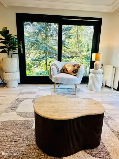 Das geräumige, helle Wohnzimmer verfügt über viele Fenster und Blick auf den umliegenden Garten