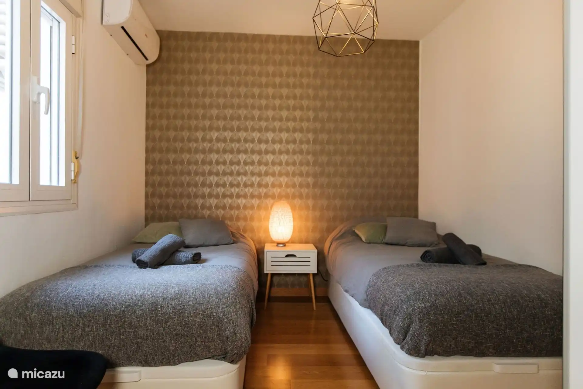 En face de la chambre double se trouve l’autre chambre avec 2 lits simples. Pas de patio privé ici, mais vous regardez par la fenêtre sur le grand patio. 