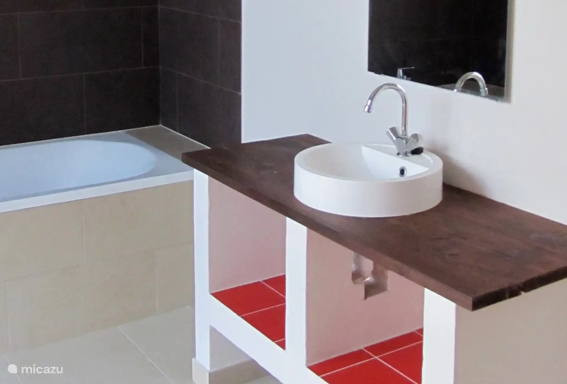 Hay dos baños grandes. Un baño tiene ducha, el amplio baño de esta foto tiene una bañera con ducha. También hay un lavabo y un inodoro.  