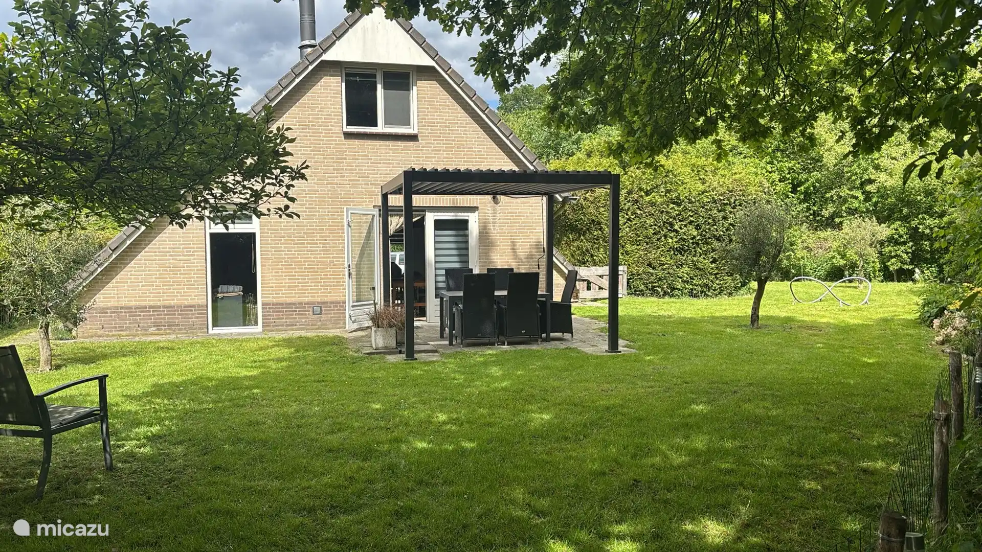 Gezellige achtertuin met lamellen pergola en comfortabele zit gelegenheid.