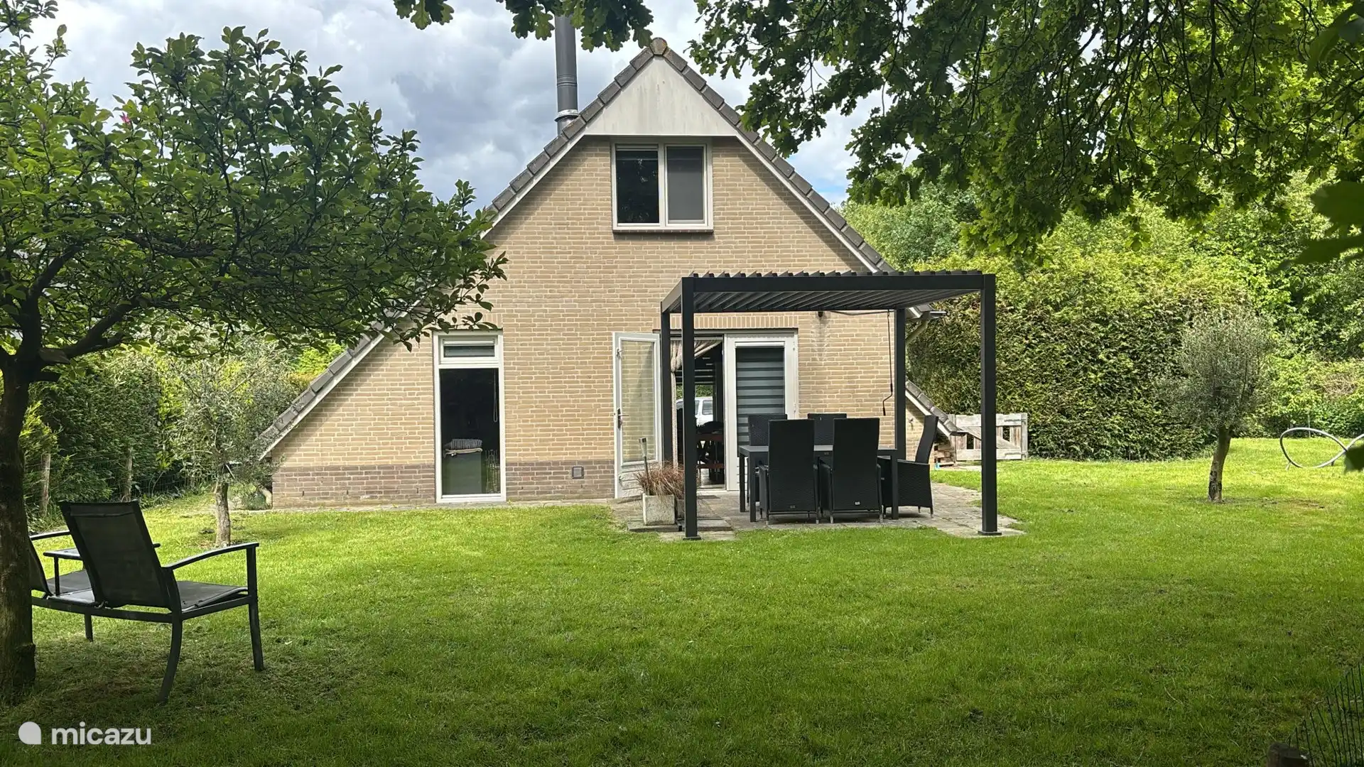 Cozy 0mheinde green backyard, privacy with slatted pergola and comfortable seating.