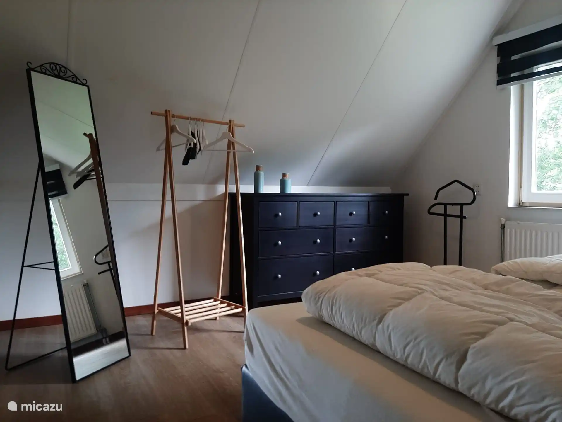 Rückenlehne des Schlafzimmers mit Kommode, Kleiderständer und Spiegel.