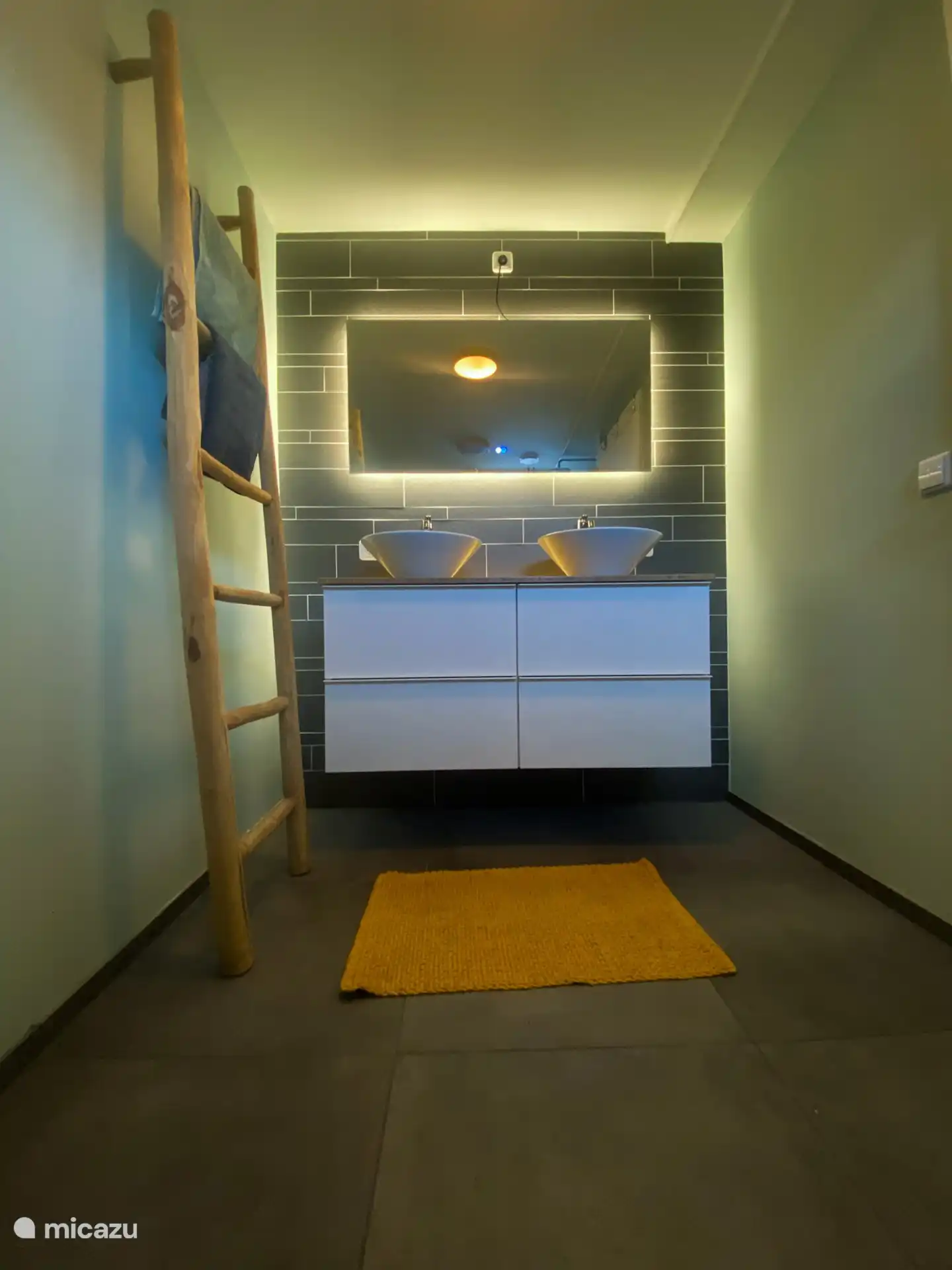 Das Badezimmer ist mit Möbeln und Doppelwaschbecken ausgestattet.