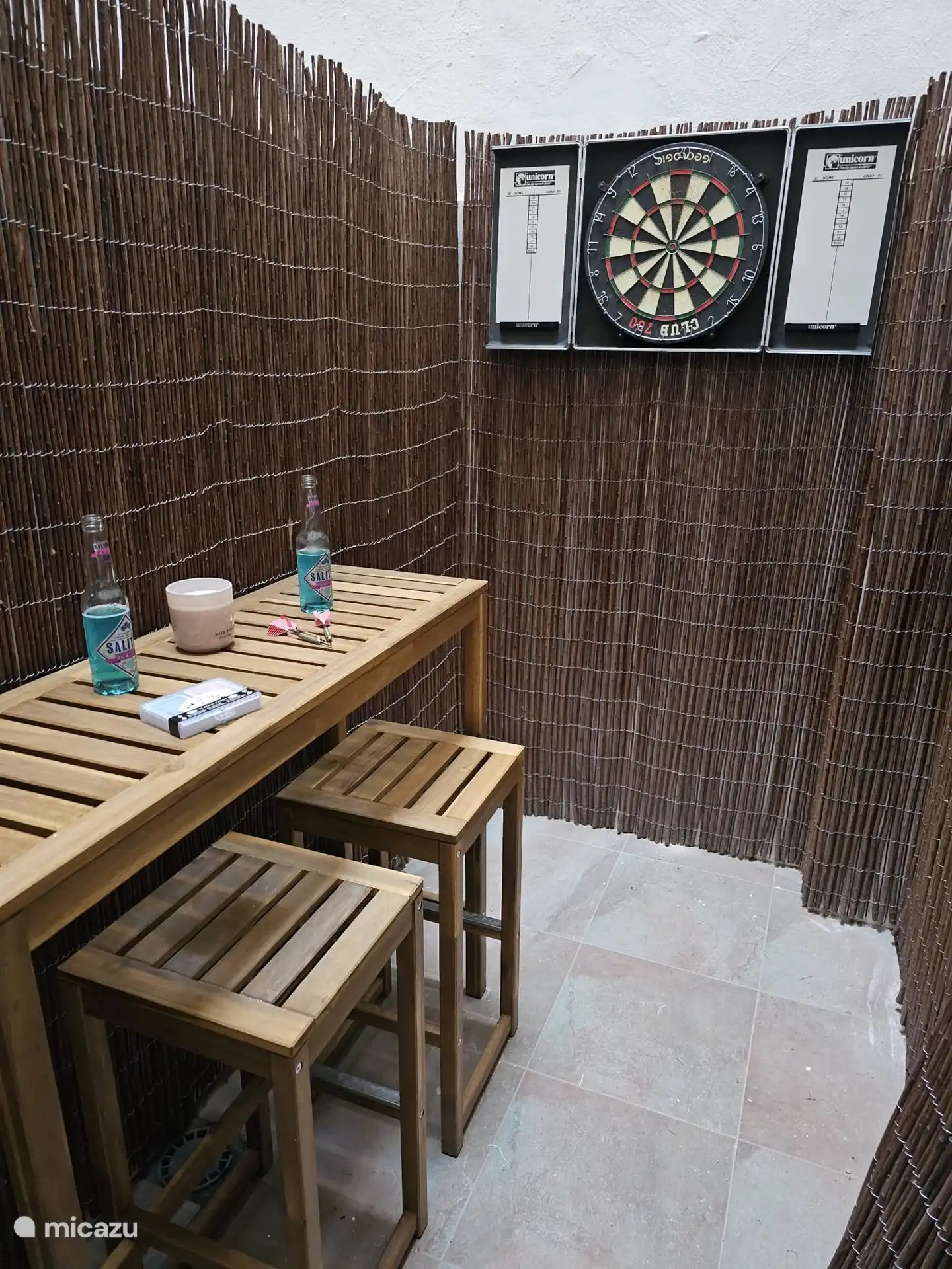 Patio with bar stools and dartboard and playing cards for fun