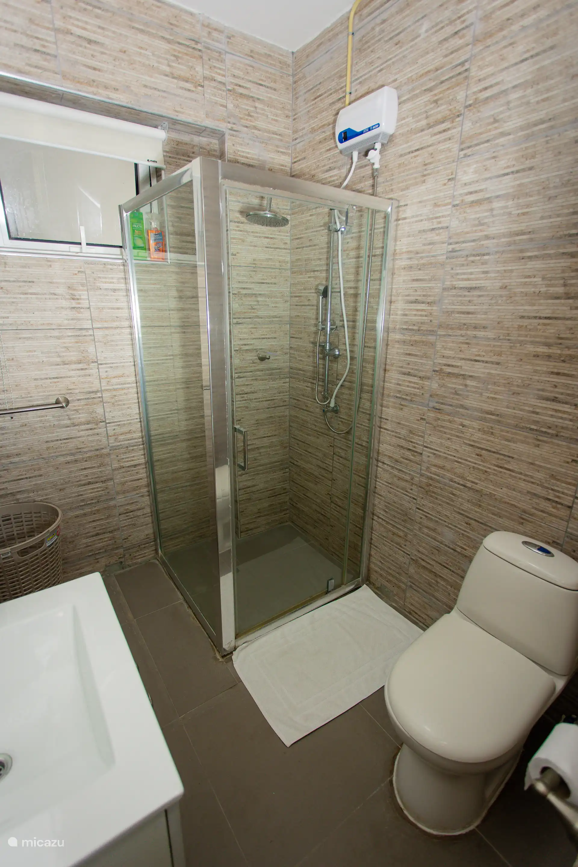 Modernes gefliestes Badezimmer mit verglaster Regendusche und allem Notwendigen vorhanden.