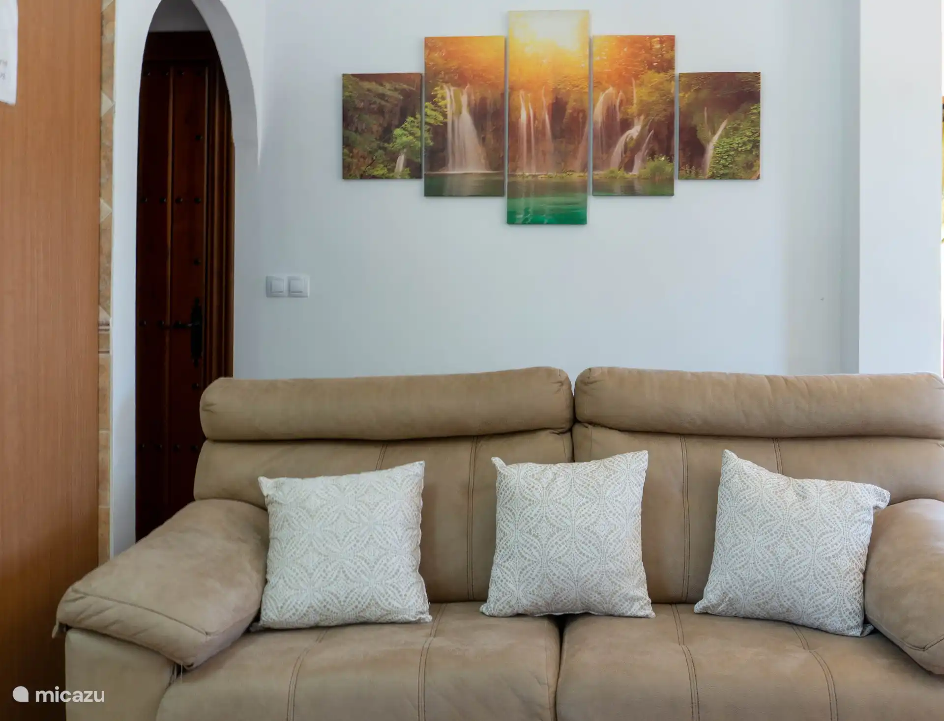 Bequemes Sofa und dahinter Zugang zu den Schlafzimmern und dem Badezimmer.