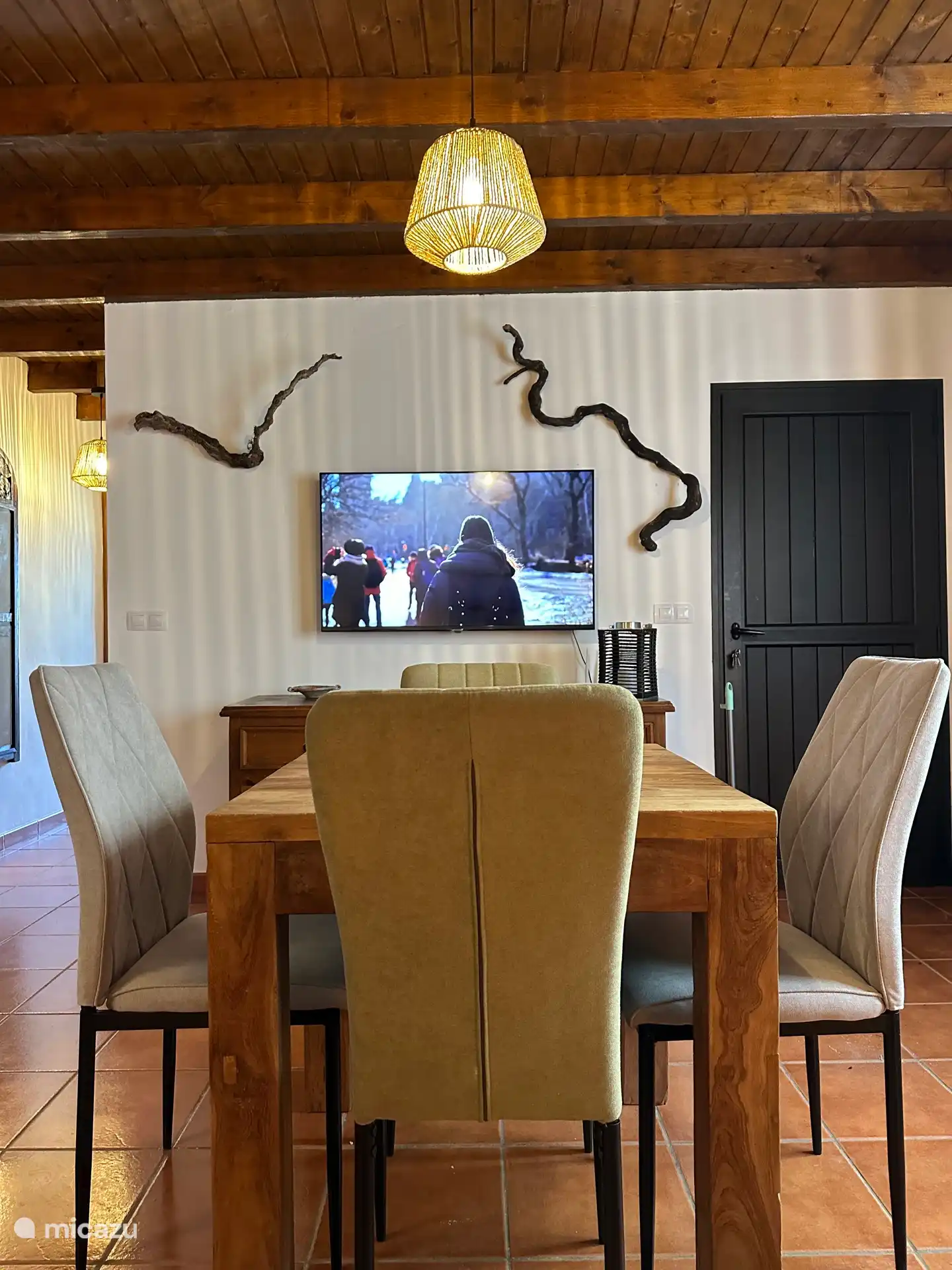 Gran televisor de pantalla plana y mesa de comedor. A la izquierda el pasillo que conduce al dormitorio