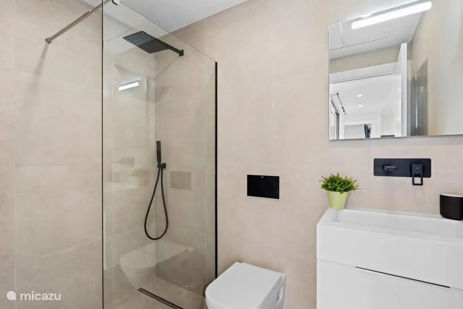 das Badezimmer mit WC, Dusche und Waschbecken 