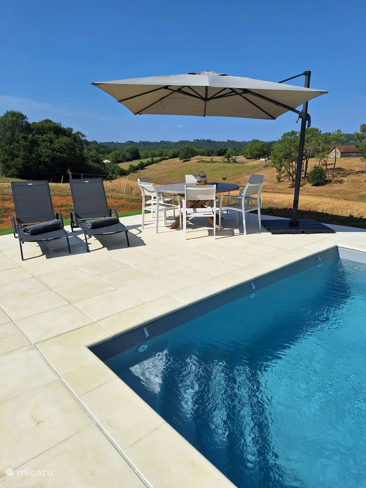 Schwimmbad mit Liegestühlen, großem Tisch und Sonnenschirm