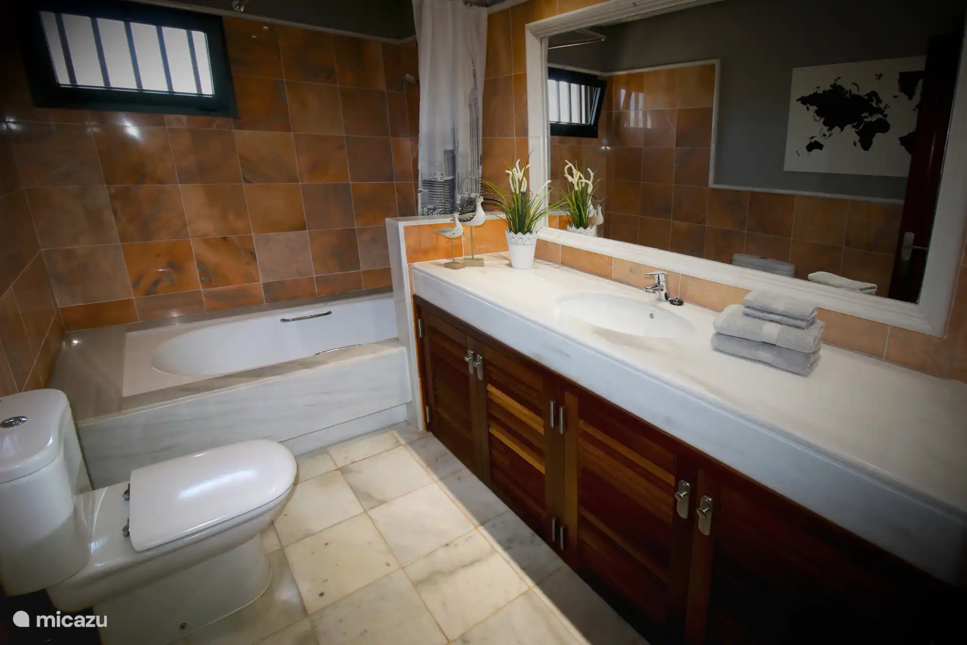 The bathroom has a large sink, bath, toilet and hair dryer 