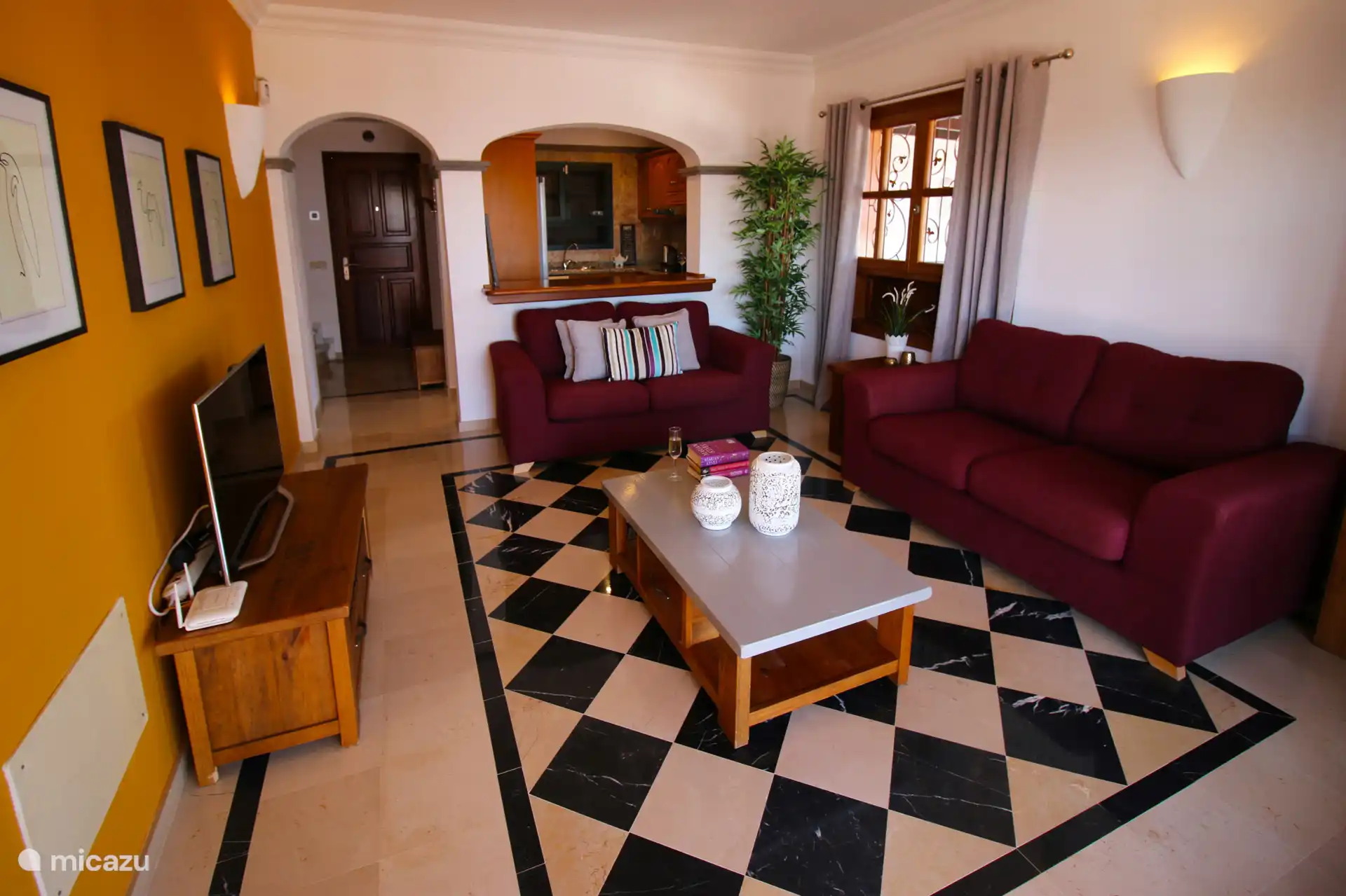 A spacious living room with two comfortable sofas and a satellite television with various international channels.