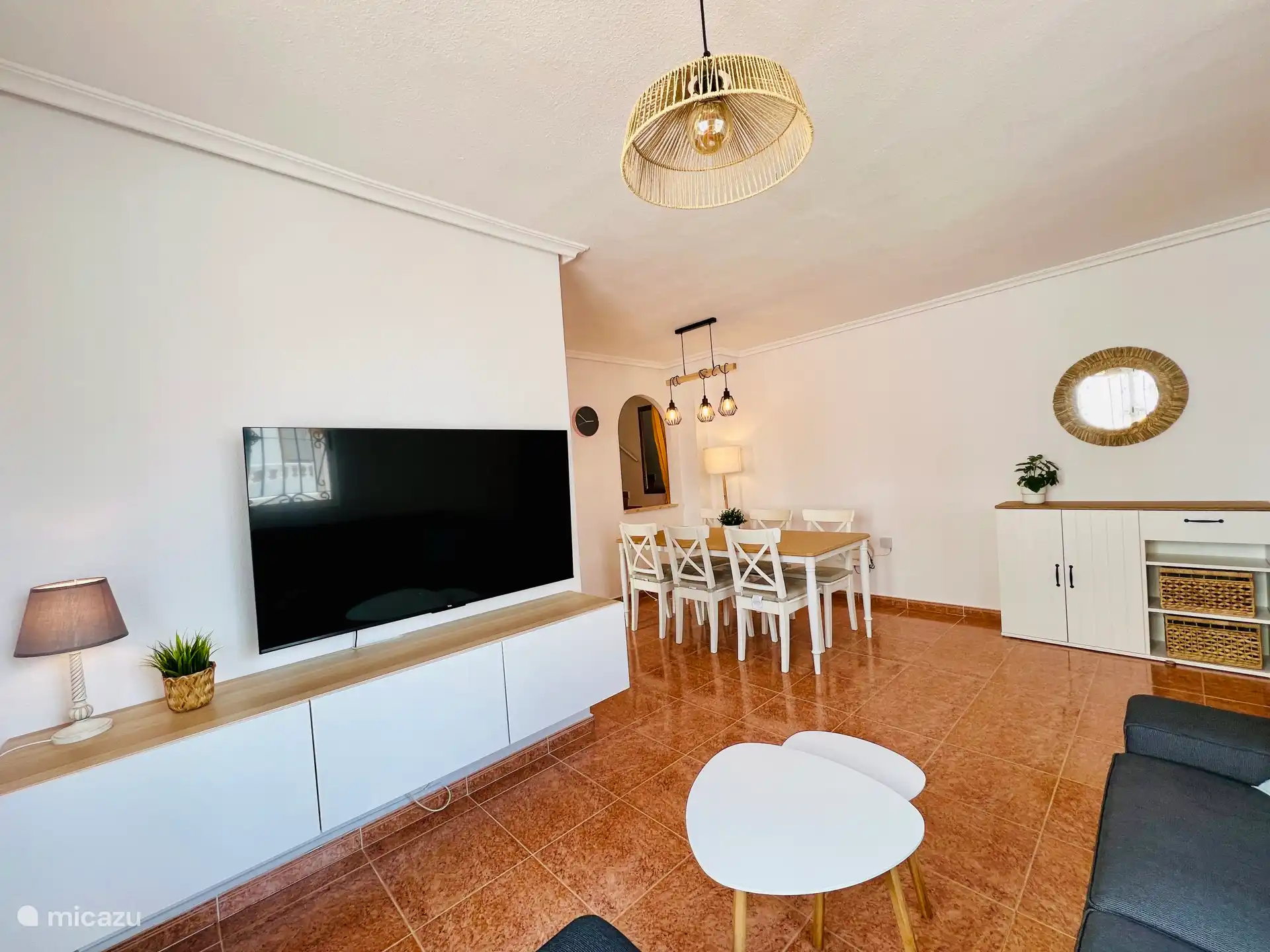 Wohnzimmer mit Lounge, Esstisch mit 6 Stühlen. Ein Hochstuhl und ein Kinderbett sind ebenfalls vorhanden. 