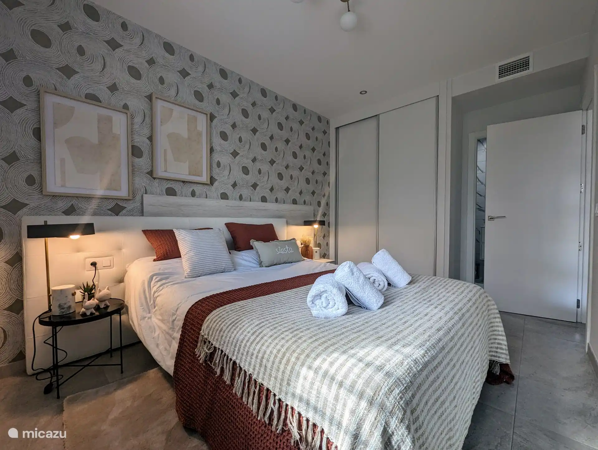 Chambre principale avec un lit double, un grand placard de rangement et la salle de bain attenante.