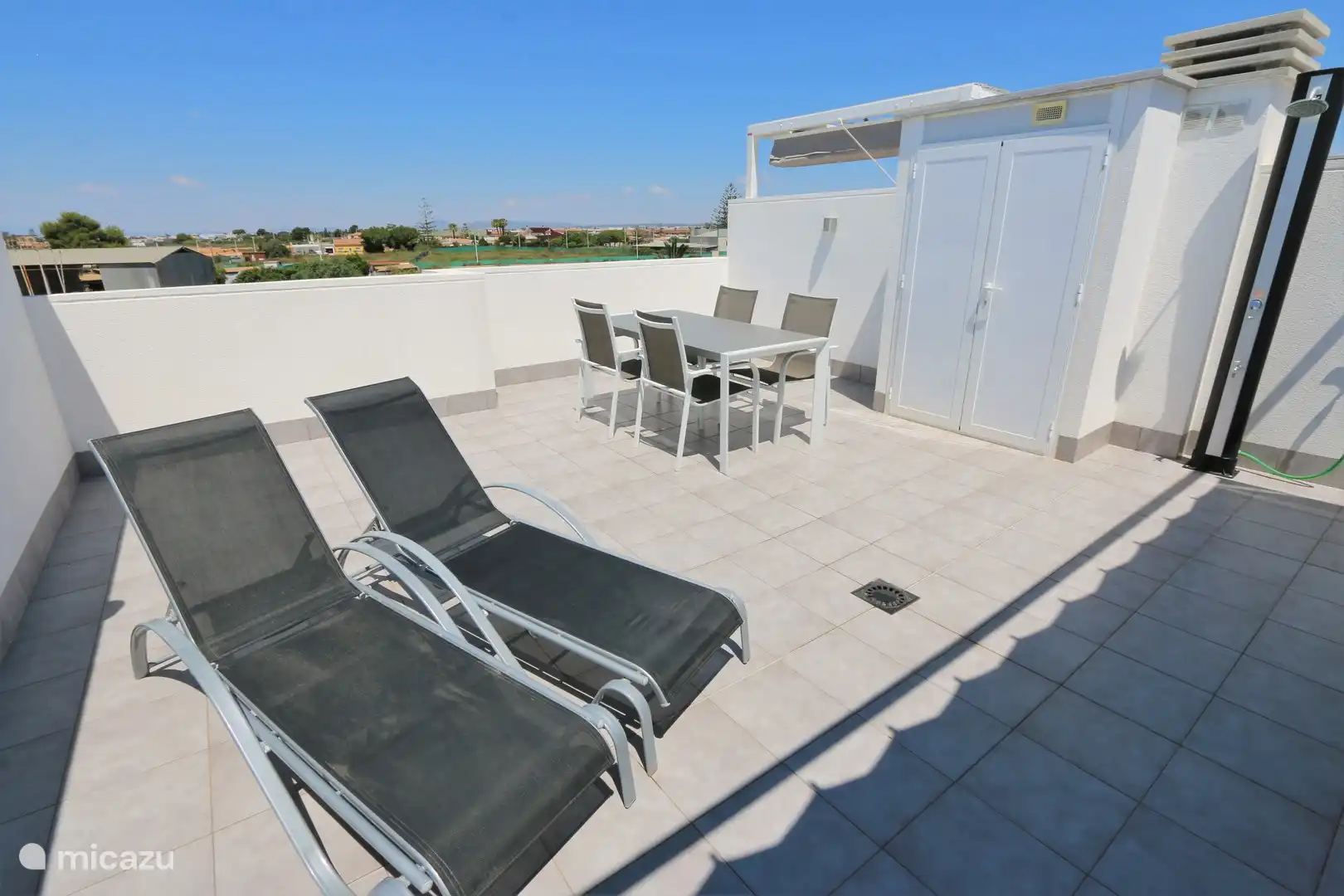 Die Dachterrasse mit Liegestühlen und Tischgarnitur