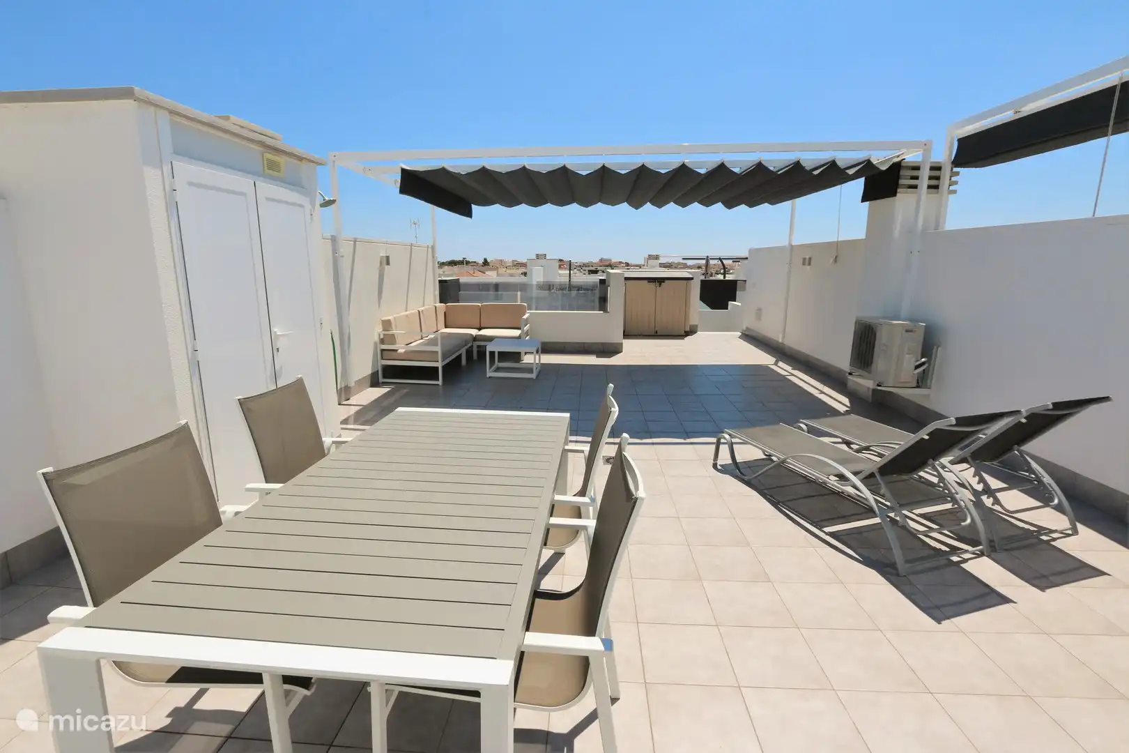 Die Dachterrasse mit Liegestühlen und Tischgarnitur