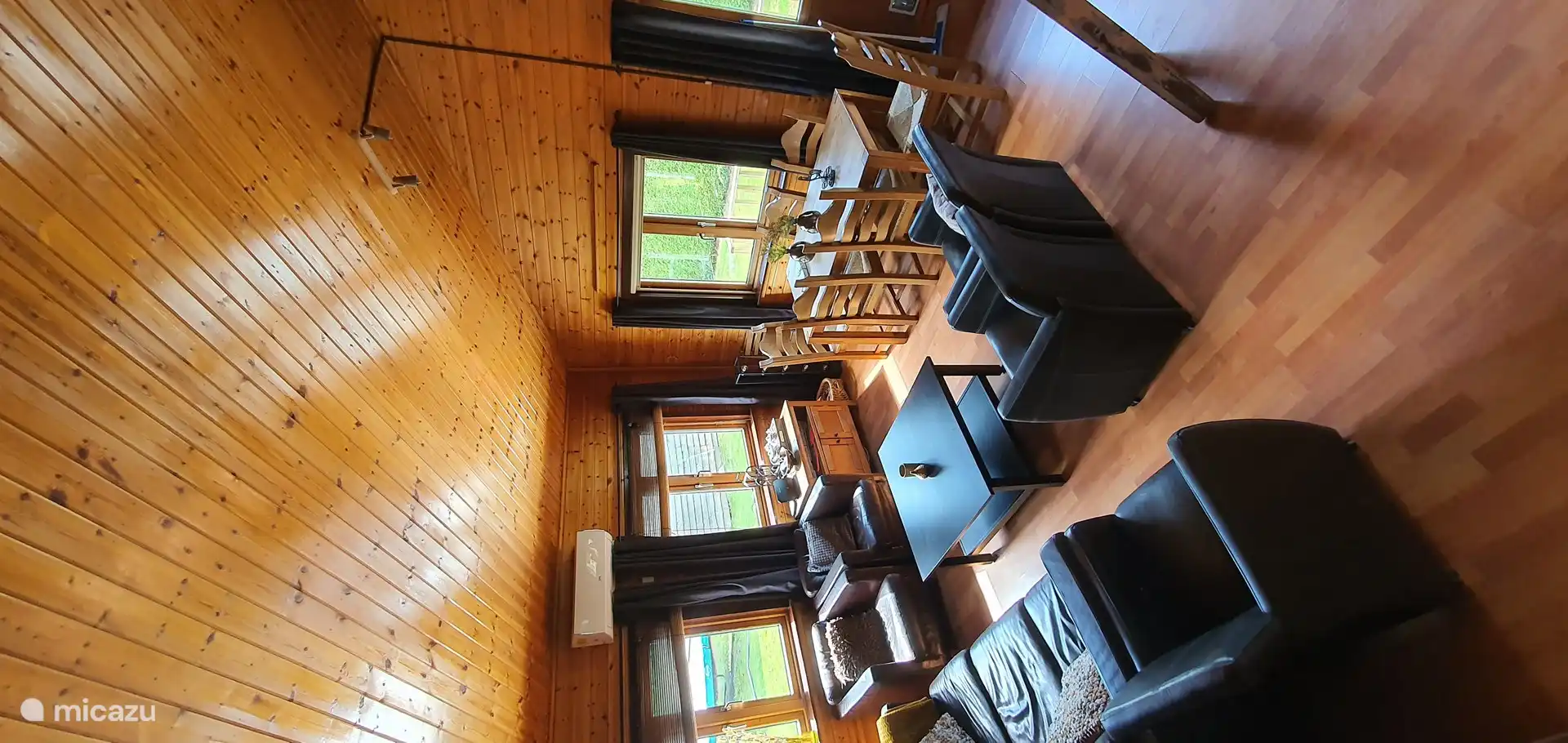 Ein Überblick über das Zimmer mit schönen Sesseln und 3-Sitzer-Sofa und dem Essbereich.