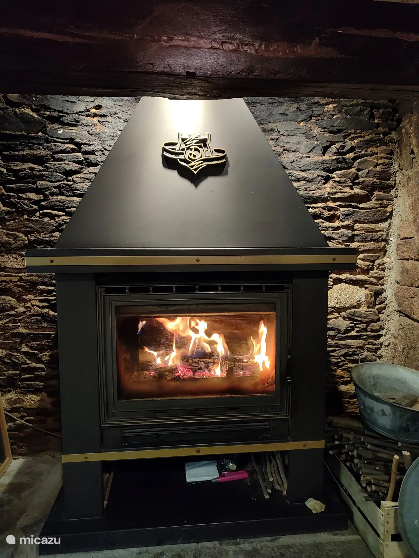 Neben dem Ofen stehen das Anzündholz und ein großer Behälter mit Holz.