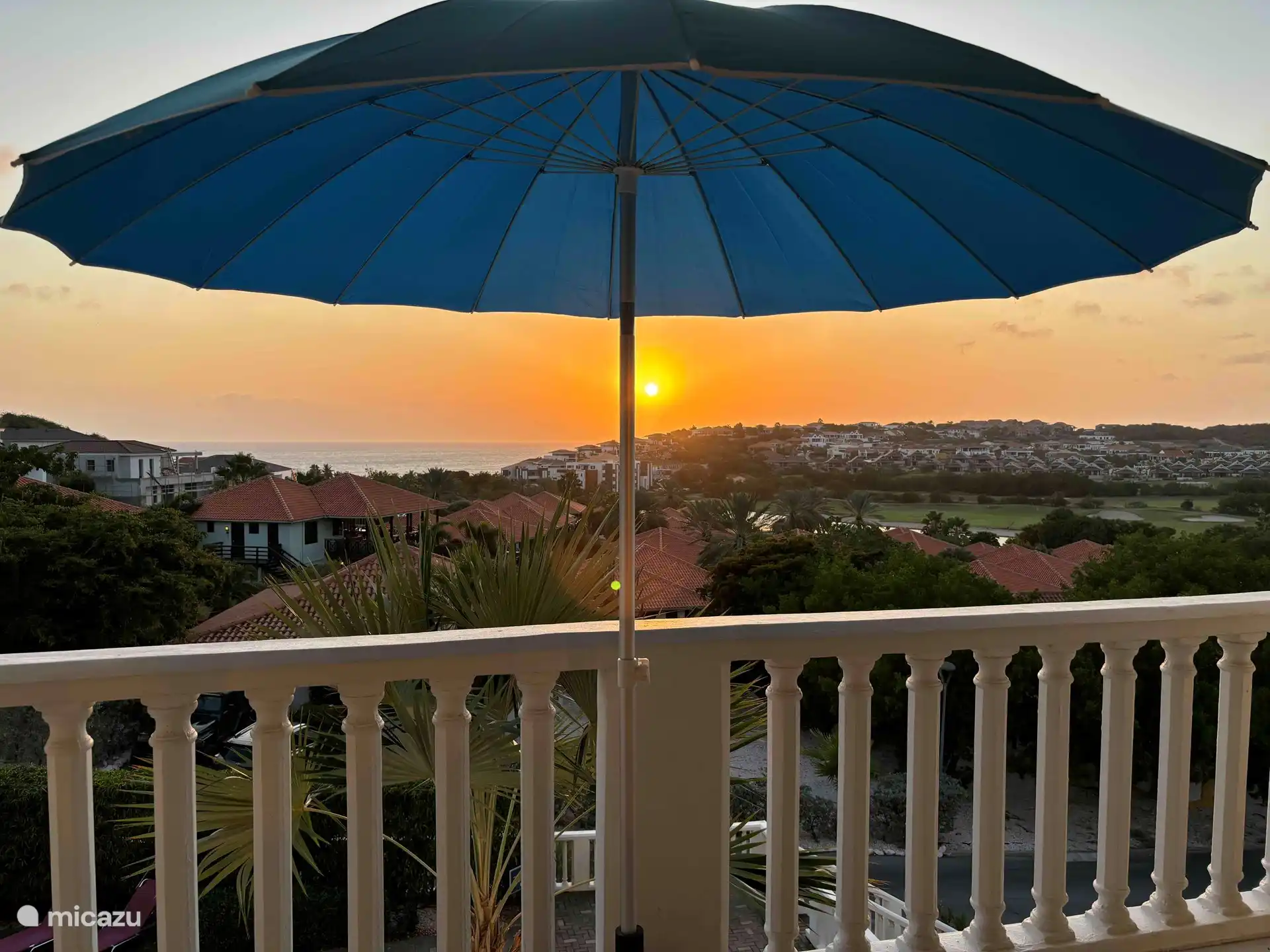 Vanaf het balkon heb je prachtig uitzicht op Blue Bay met een ondergaande zon