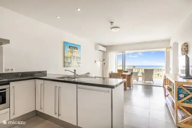 Woonkamer met open keuken en uitzicht op zee.