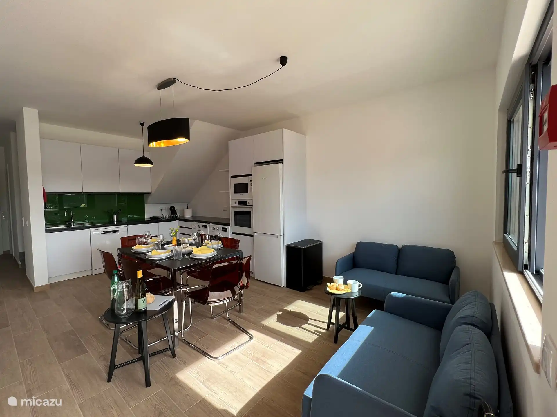 Breiterer Blick auf die Küche und das Esszimmer, das über zwei Doppelsitzsofas und den LG-Bildschirm verfügt