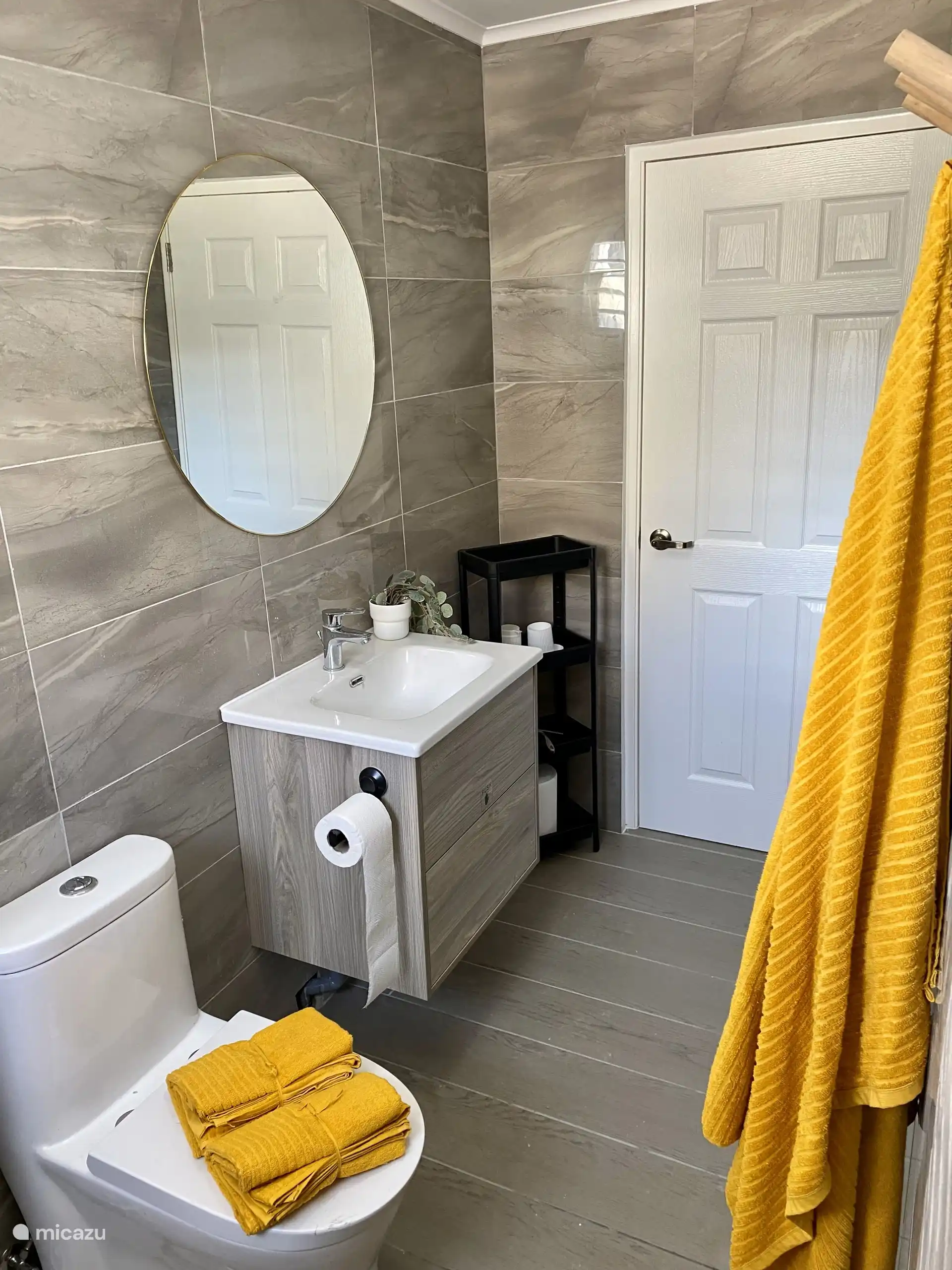 Salle de bain avec lavabo moderne, miroir spacieux, serviettes et espace de rangement pratique - tout pour un séjour confortable.