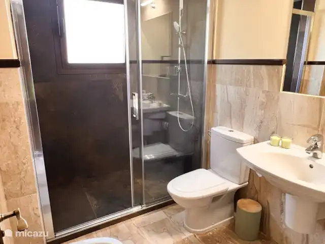 Finca San Antonio - Luxe Appartement huren in Spanje, Andalusië, Mijas - appartement De gastenbadkamer is straalt eenvoud en comfort uit. Geniet van een luxe douche-ervaring in de ruime inloop regendouche met glazen schuifwand. Voor extra gemak zijn een toilet en bidet aanwezig.