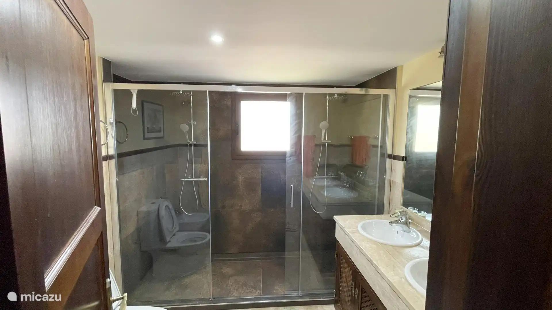 El ba&#241;o en suite ofrece una sofisticada combinaci&#243;n de lujo y dise&#241;o elegante. Disfrute de una ducha vigorizante bajo la ducha de lluvia doble, elegantemente separada por una pared corrediza de vidrio.