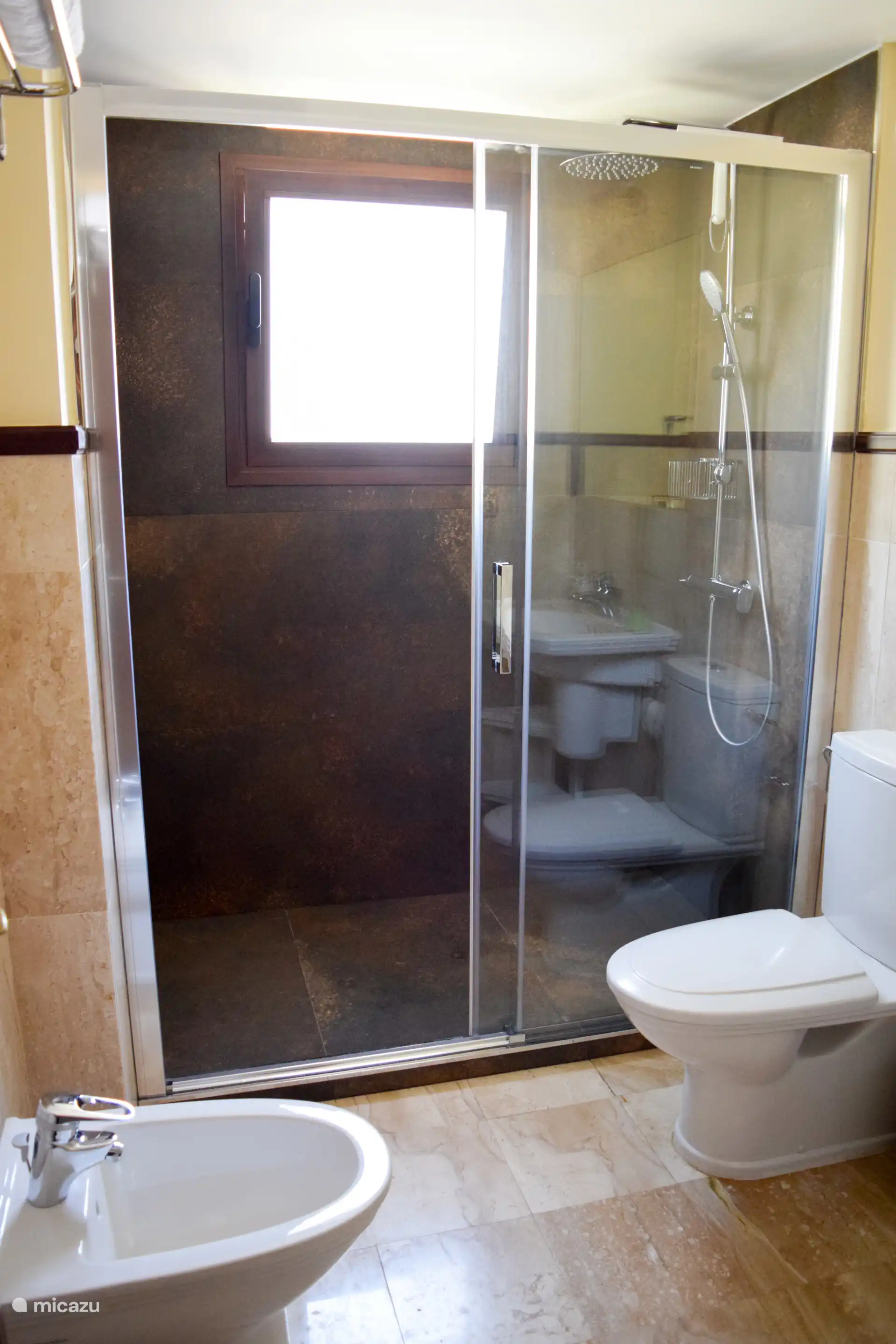 Disfrute de una lujosa experiencia de ducha en la espaciosa ducha de efecto lluvia con pared de vidrio deslizante.