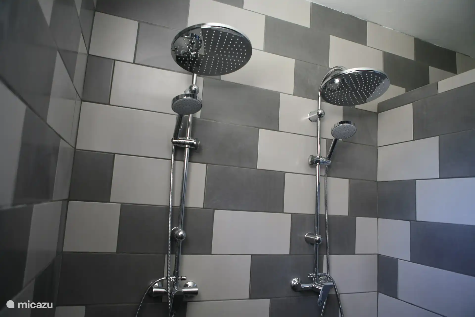 El cuarto de baño tiene un inodoro colgante, un lavabo grande, una lavadora y una amplia ducha con doble cabezal de ducha.