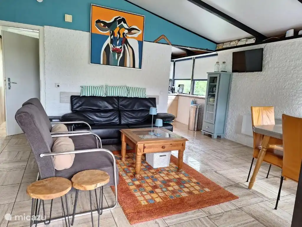 Gemütliches Wohnzimmer mit erhöhter Decke und Zugang zur Küche.