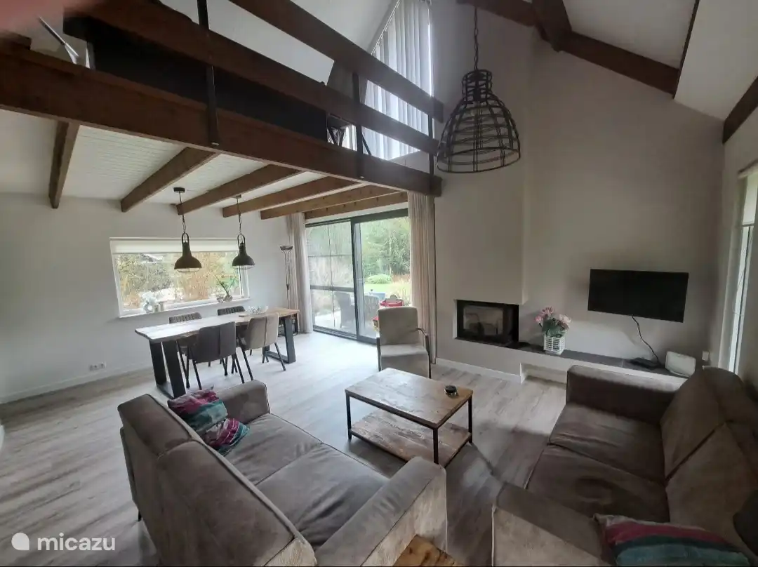 In 2026 gerenoveerde moderne woonkamer met haard, nieuwe keuken,grote glazenschuifpui naar buitenterras.