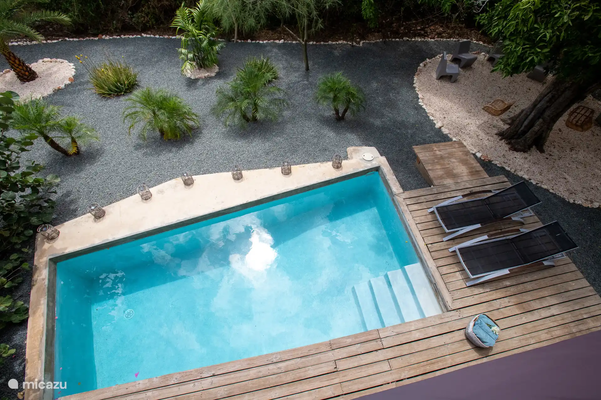 Der private Swimmingpool mit Liegestühlen und einem schön angelegten Garten