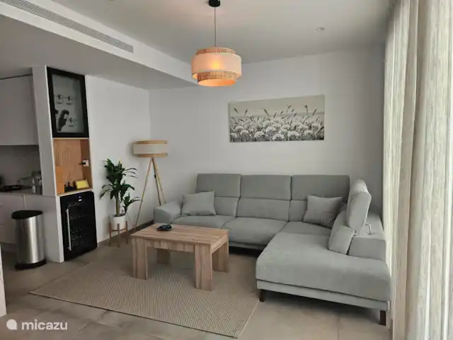 Casa Sol Y Mar | Espagne, Murcia, San Pedro del Pinatar - appartement Le salon confortable avec beaucoup d’accents de blanc et de bois combiné à la verdure estivale. L’éclairage crée une atmosphère chaleureuse le soir.