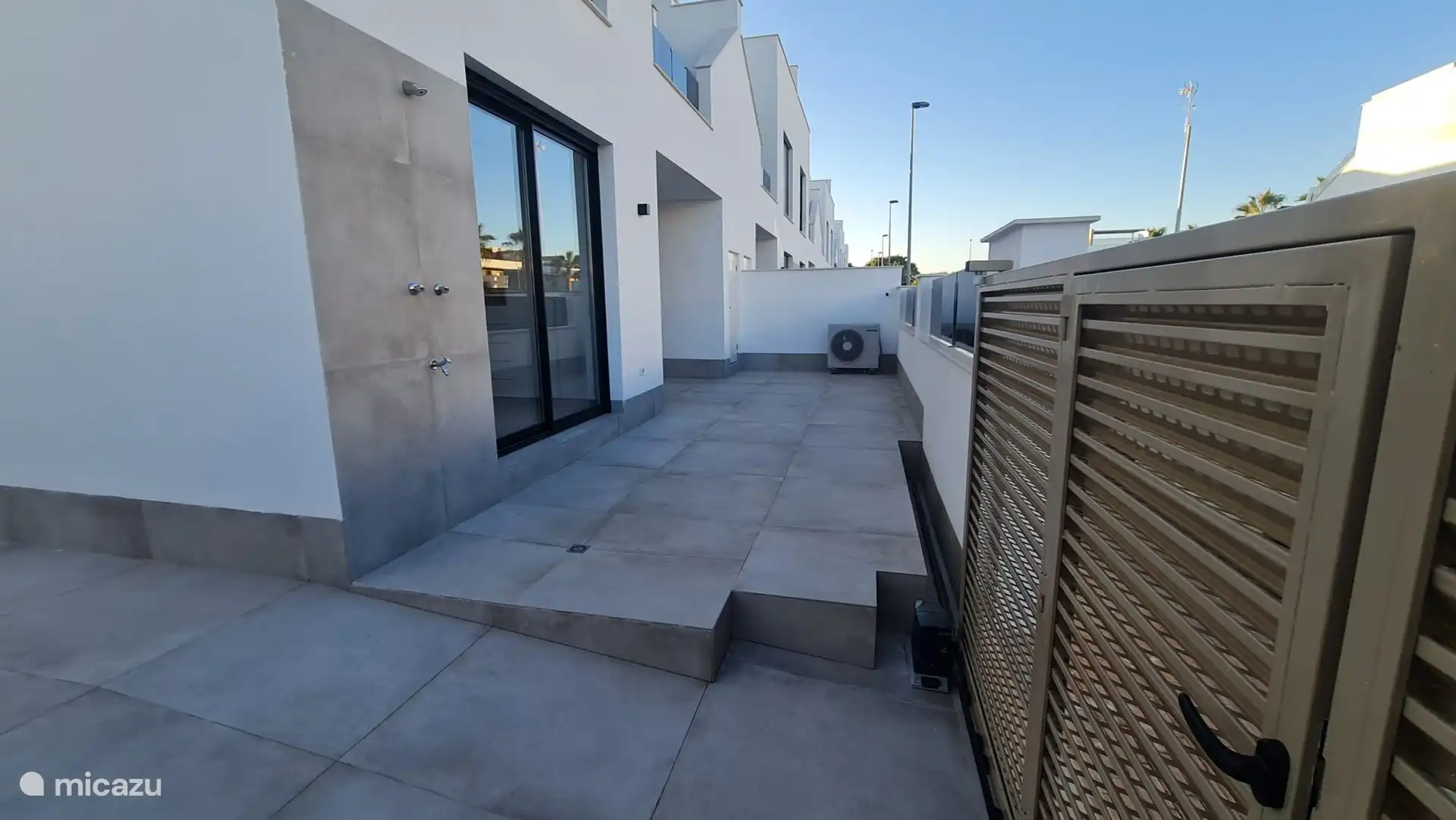 Appartement à l’avant / entrée avec douche extérieure et portes coulissantes chambre principale. 