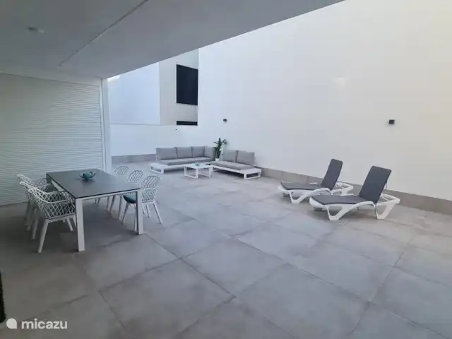 Casa Sol Y Mar | Espagne, Murcia, San Pedro del Pinatar - appartement De la partie couverte de la terrasse, une vue sur l’ensemble de la terrasse. Sous le baldaquin, une table pour six personnes avec des chaises et des coussins. Sur la terrasse un coin salon.