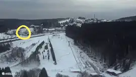 Uitzicht vanaf de skischans op het huis in de winterperiode. De Stoeltjeslift en skipistes liggen recht voor het huis. 