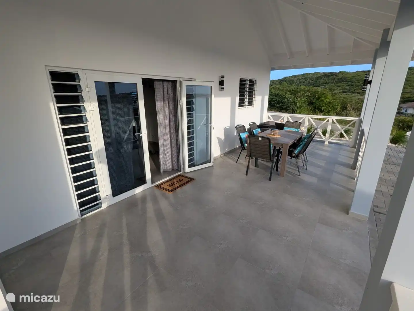 Hoofdveranda aan de voorzijde en hoofdingang, met eethoek buiten en extra zitplaatsen