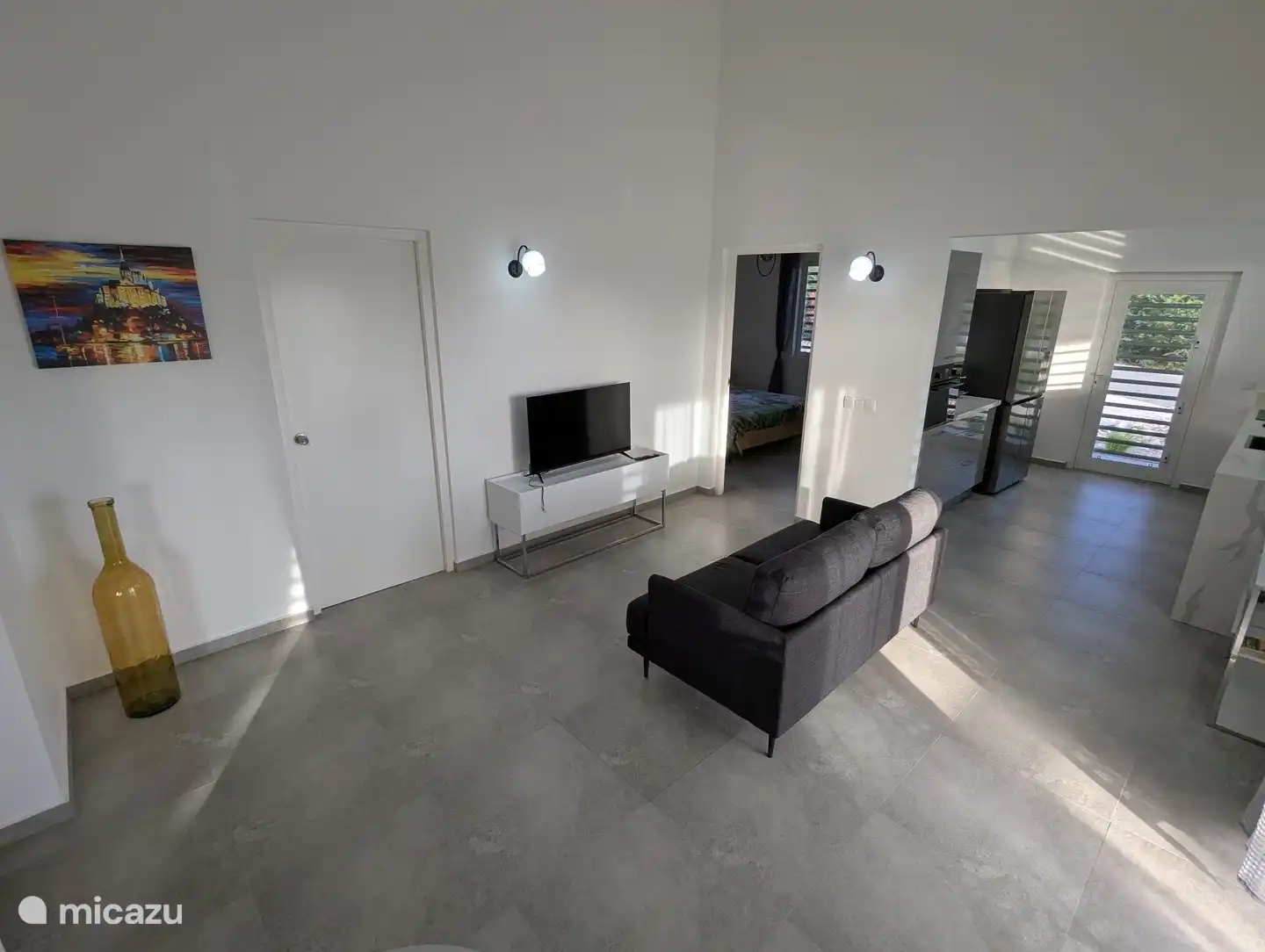 Binnen woonkamer, doorkijk naar keuken en hoofdslaapkamer. Deur naar berging en wasruimte aan de linkerkant