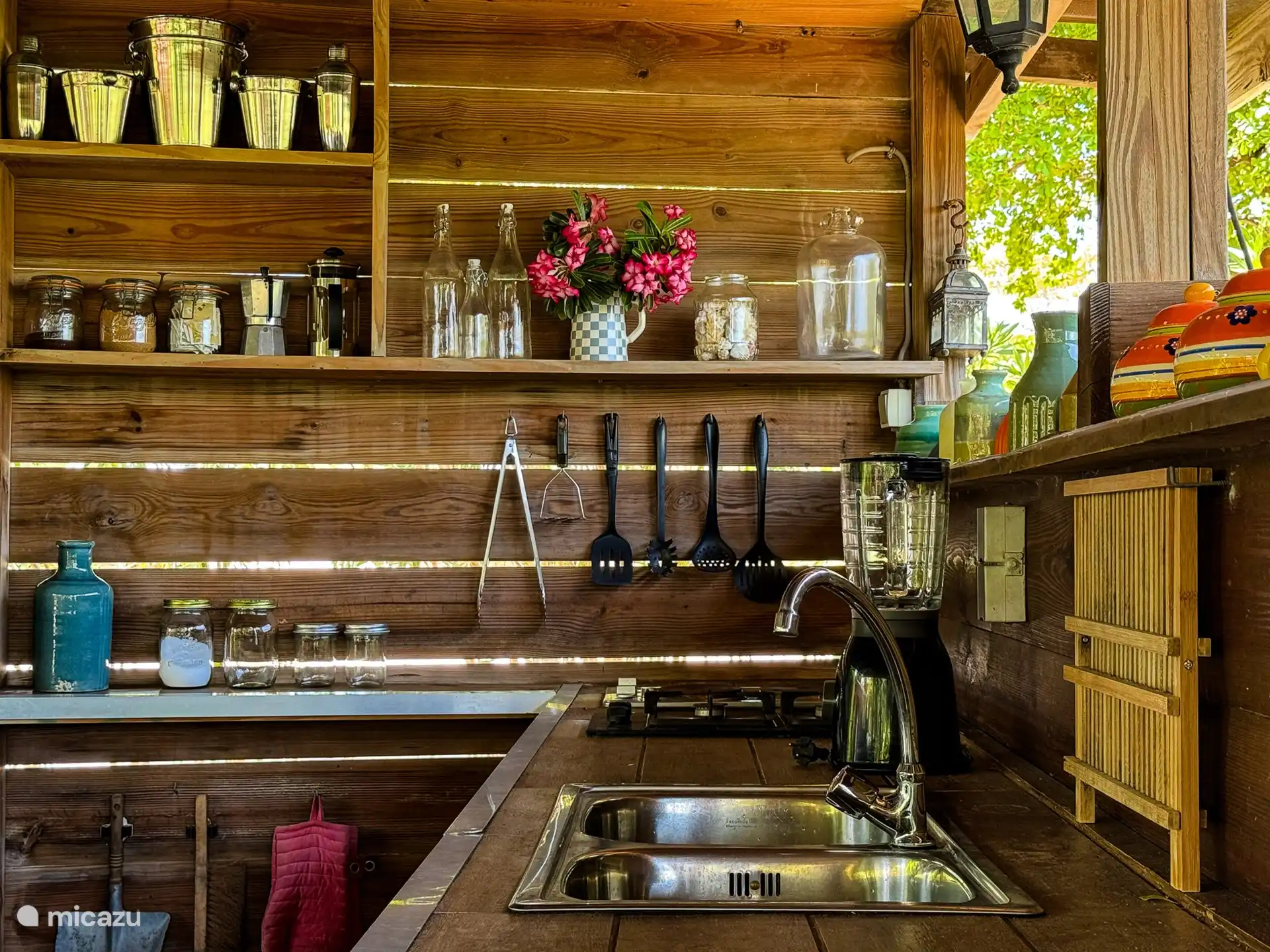 Frente a los estudios hay una gran cocina al aire libre con una terraza sombreada. Un lugar resguardado donde el viento siempre refresca y es maravilloso alojarse. La cocina al aire libre está totalmente equipada con estufa, placa grill, prensa francesa, hervidor de agua, licuadora, etc. Hay asientos de bar alrededor de la cocina y hay 