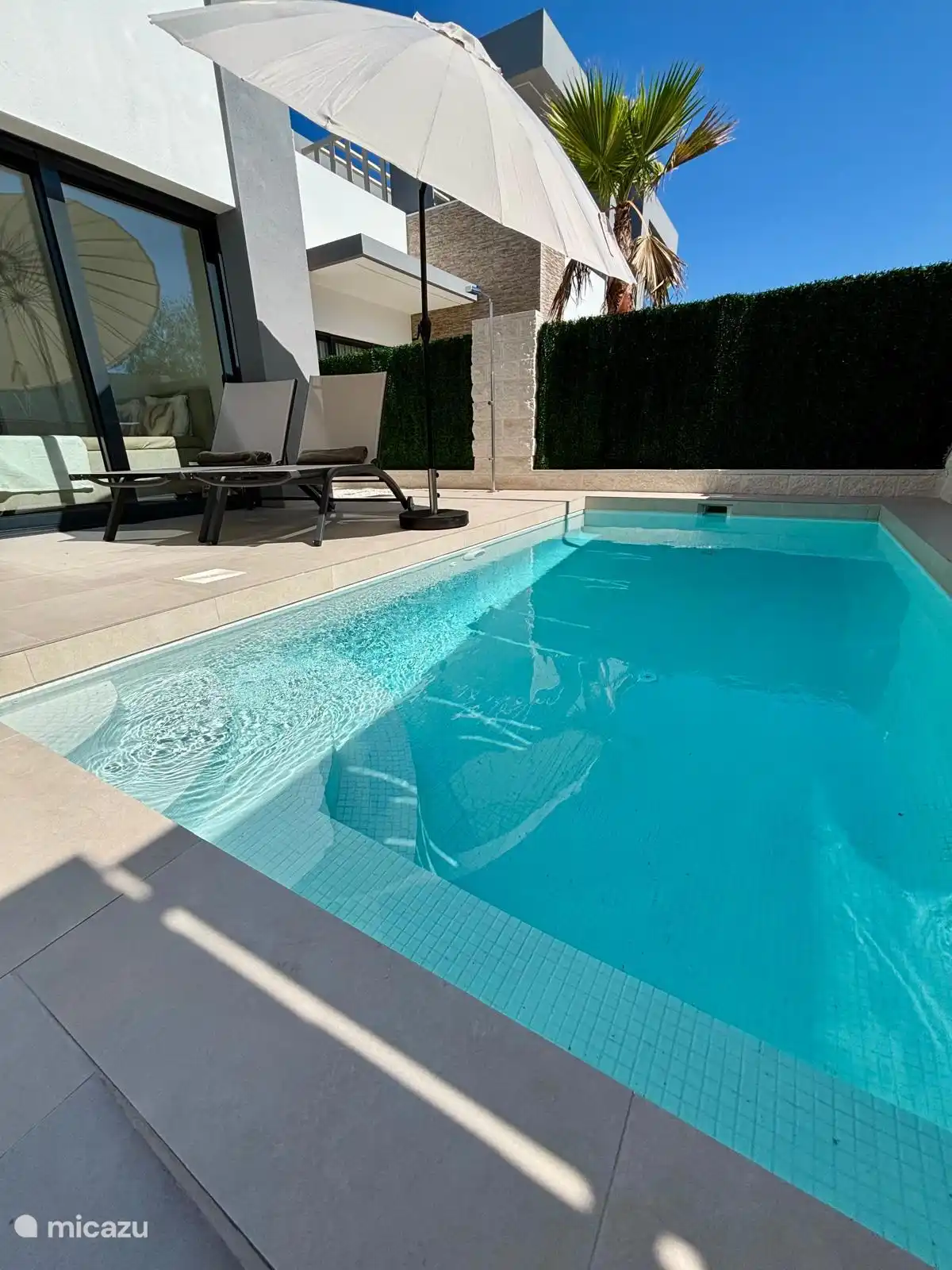 Zwembad met ligbedden en parasol