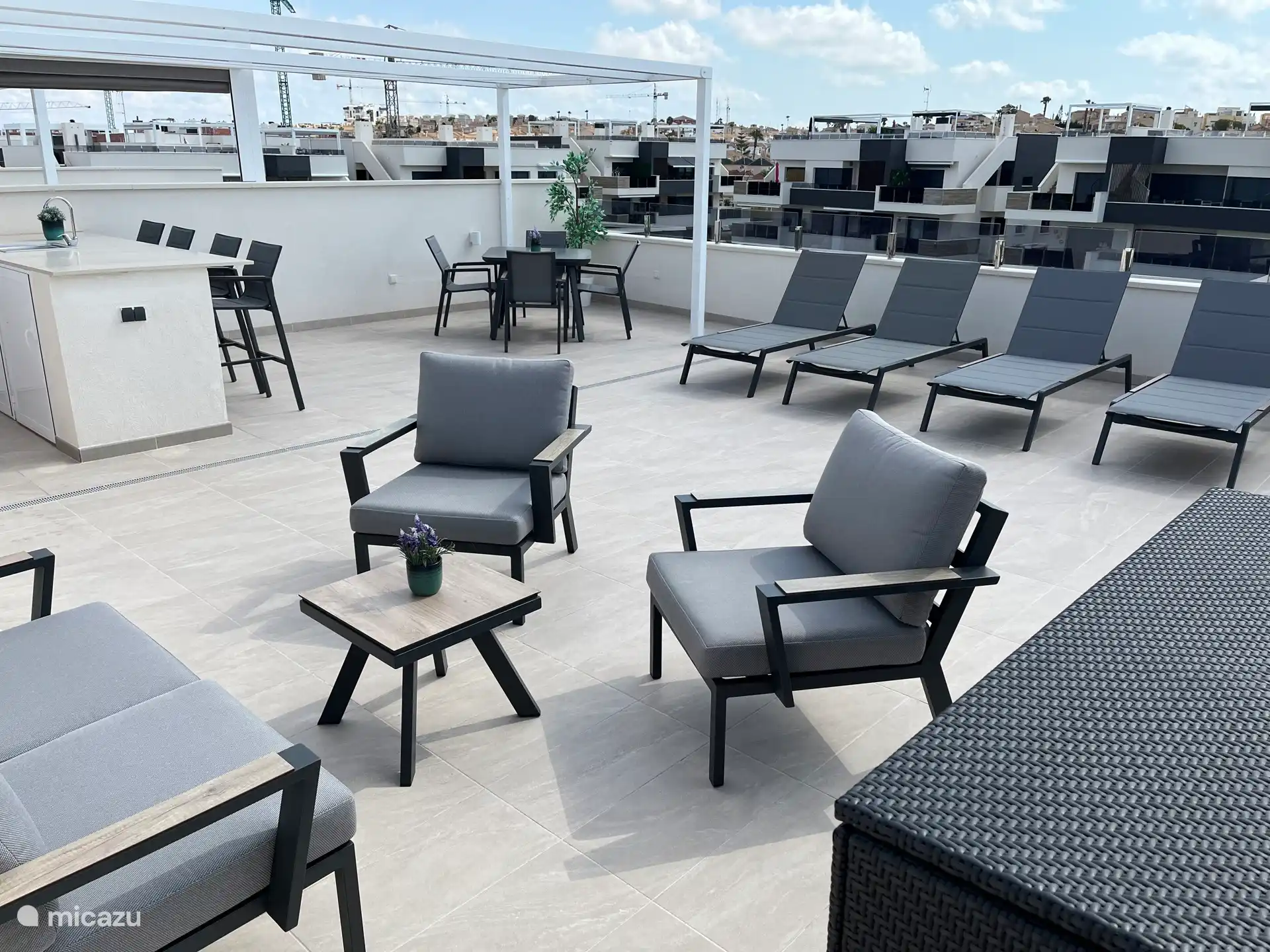 Terrasse sur le toit avec cuisine extérieure, table à manger, coin salon et chaises longues