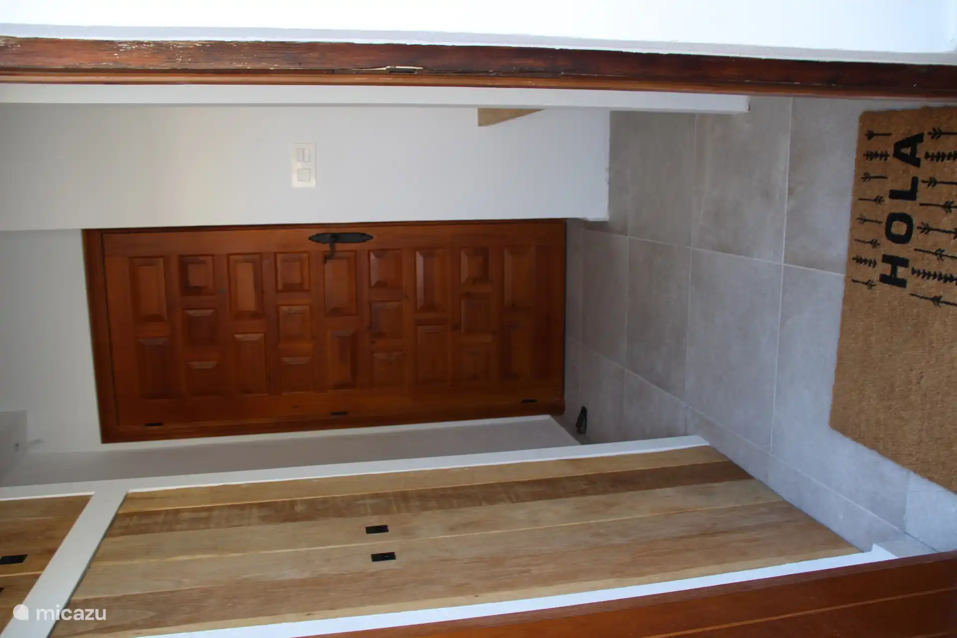 La entrada tiene un perchero y un espacio de armario con un lavadero con lavadora al lado