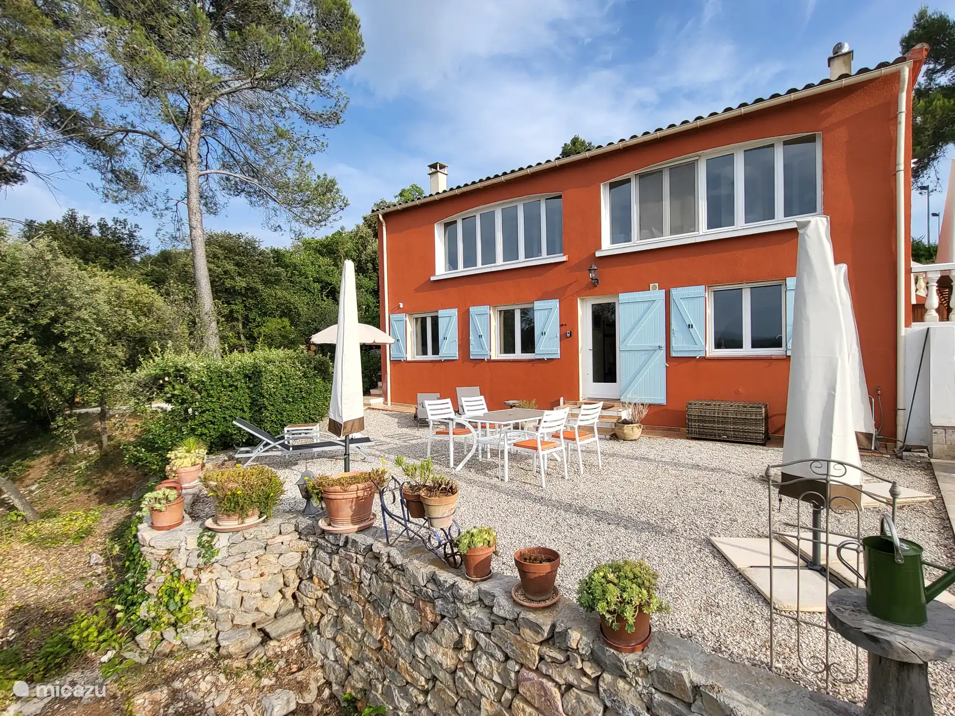 Terrasse im Erdgeschoss mit Esstisch für vier Personen und mehreren Sonnenliegen mit Sonnenschirmen