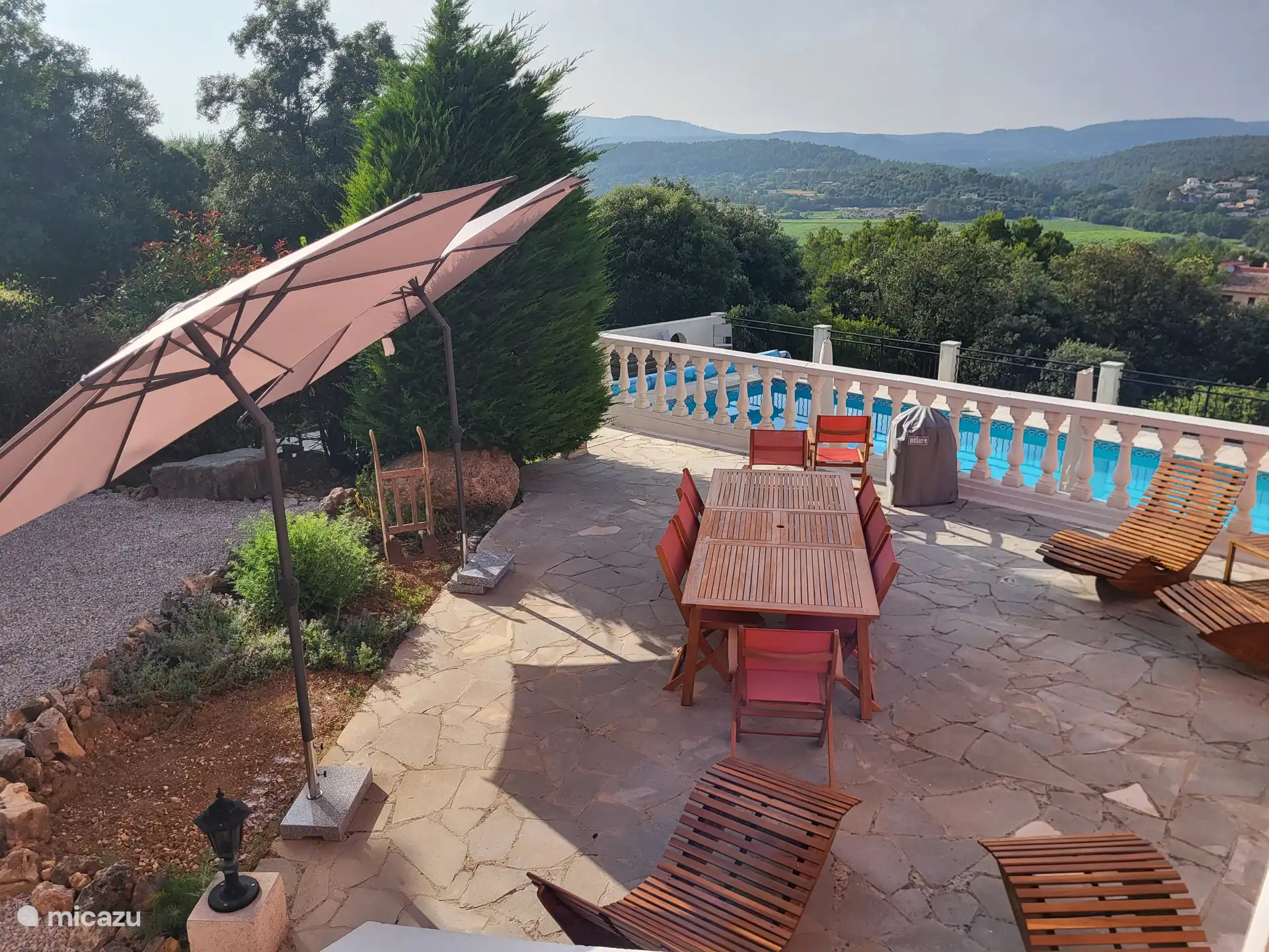 Terrasse im Obergeschoss mit Esstisch für 10 Personen und vier Sonnenliegen aus Holz